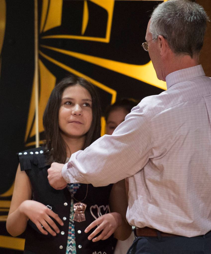 Mckayla Marks receives her promotion copper Tinaa from Paraeducator Patrick Minick at the Tlingit Culture Language & Literacy 5th Grade Promotion held in the clan house at the Walter Soboleff Center on Wednesday, May 22, 2019. (Michael Penn | Juneau Empire)
