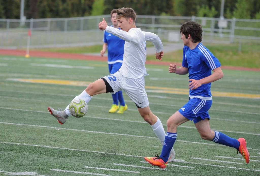 Thunder Mountains Wallace Adams reaches for the ball between a pair of unidentified Monroe Catholic players during the first half of their ASAA/First National Bank Alaska soccer state championship match Thursday evening at Service High School in Anchorage. (Michael Dinneen | For the Juneau Empire)