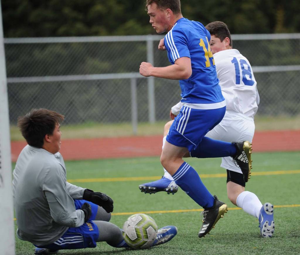 Thunder Mountains Matthew Hartsock, right, challenges Monroe Catholics Joshua Gray and keeper Trae Puryear with a shot during their ASAA/First National Bank Alaska soccer state championship match with Monroe Catholic Thursday evening at Service High School in Anchorage. (Michael Dinneen | For the Juneau Empire)
