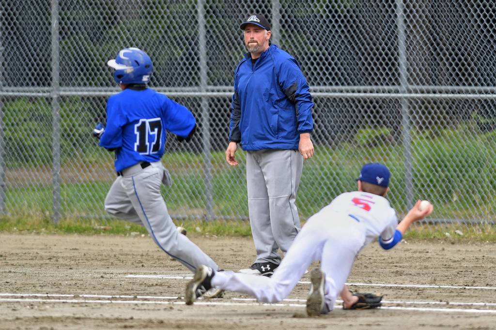 Thunder Mountains Assistant Coach Jake Carte watches as Isaiah Nelson, left, outruns the throw by Sitkas pitcher Cole Riggs during the Region V Baseball Championship at Adair-Kennedy Memorial Park on Friday, May 24, 2019. (Michael Penn | Juneau Empire)