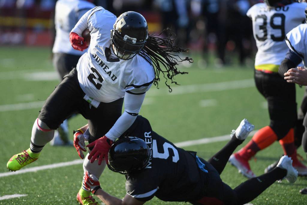 Legends Jake Miller, right, tackles Stars Silver Maake during the Juneau Alumni Football Game with football players, dance team members and cheerleaders from Juneau-Douglas and Thunder Mountain High Schools at Adair-Kennedy Memorial Field on Friday, May 24, 2019. (Michael Penn | Juneau Empire)
