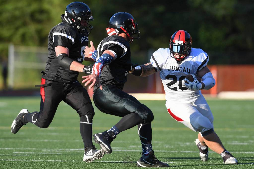 Stars Lance Fenumiai, right, is pursued by Legends Tommy Penrose, center, and Jake Ritter in the Juneau Alumni Football Game with football players, dance team members and cheerleaders from Juneau-Douglas and Thunder Mountain High Schools at Adair-Kennedy Memorial Field on Friday, May 24, 2019. (Michael Penn | Juneau Empire)