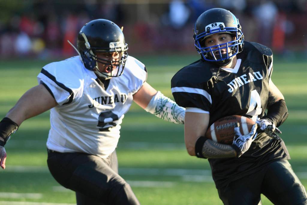 Legends Matthew Maka, right, is chased by Stars Romney Tupou in the Juneau Alumni Football Game with football players, dance team members and cheerleaders from Juneau-Douglas and Thunder Mountain High Schools at Adair-Kennedy Memorial Field on Friday, May 24, 2019. (Michael Penn | Juneau Empire)