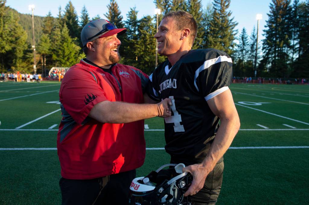 Chad Bentz congratulates Legends Josh Dean on his touchdown during the Juneau Alumni Football Game with football players, dance team members and cheerleaders from Juneau-Douglas and Thunder Mountain High Schools at Adair-Kennedy Memorial Field on Friday, May 24, 2019. (Michael Penn | Juneau Empire)
