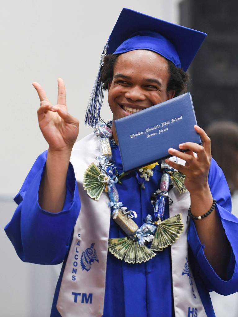 Simon Smith shows off his new diploma while walking off stage during the Thunder Mountain High School graduation on Sunday, May 26, 2019. (Michael Penn | Juneau Empire)