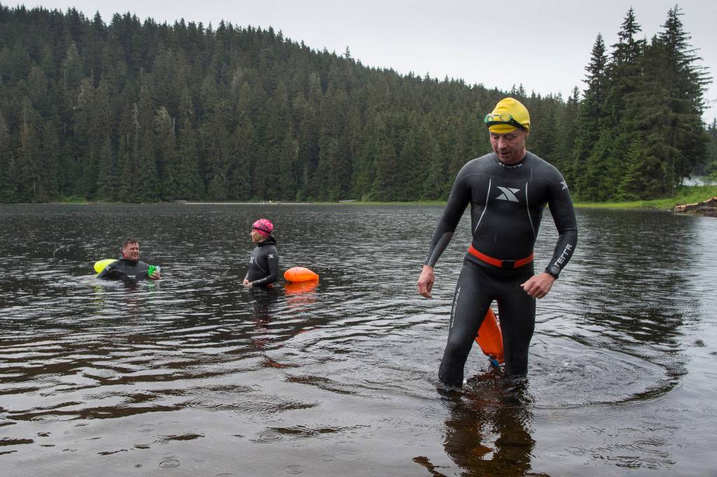 Mark Neidhold, right, exits Auke Lake with Jamie Bursell, center, and Scott Gende as swimmers train on Wednesday, June 5, 2019. (Michael Penn | Juneau Empire)