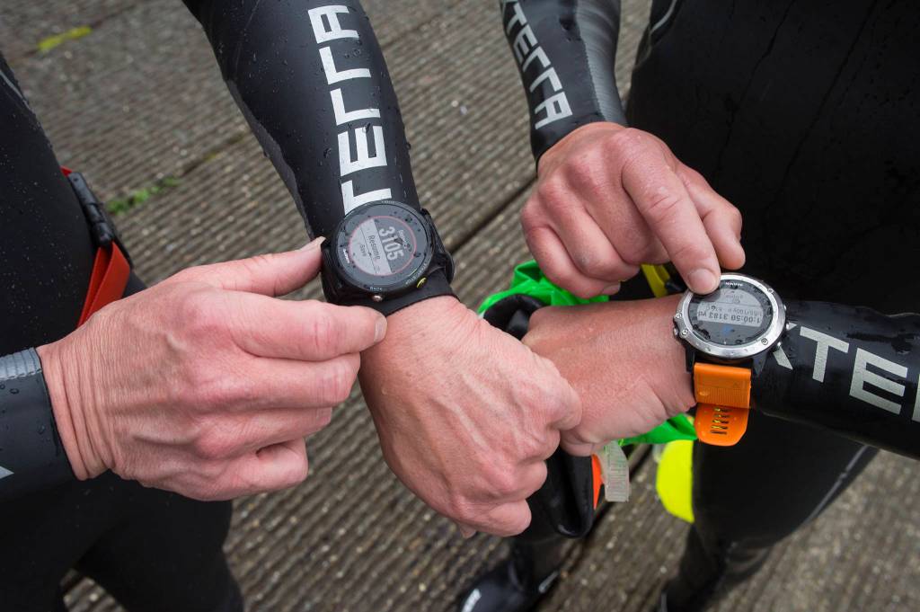 Mark Neidhold and Scott Gende check their time and distance after a training swim in Auke Lake on Wednesday, June 5, 2019. (Michael Penn | Juneau Empire)