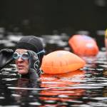 Amy Carroll adjusts her goggles while training with other swimmers in Auke Lake on Wednesday, June 5, 2019. (Michael Penn | Juneau Empire)
