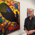 Rick Clair stands next to his oil painting Ravenhood in the Juneau Arts and Humanities Councils Juried Art Show for First Friday on Friday, June 7, 2019. (Michael Penn | Juneau Empire)