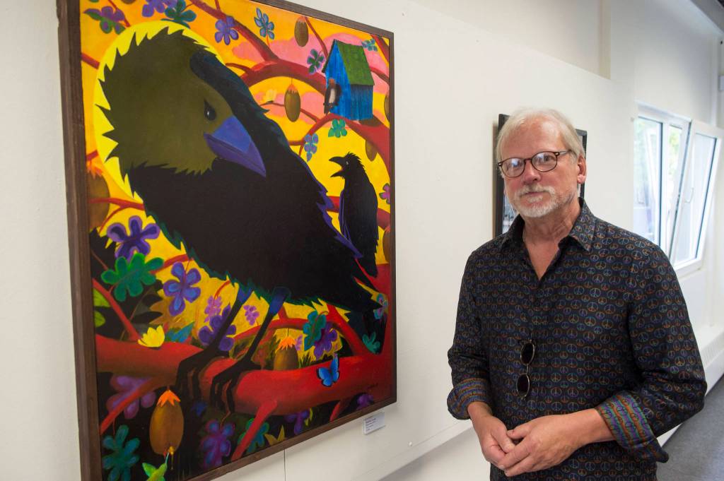 Rick Clair stands next to his oil painting Ravenhood in the Juneau Arts and Humanities Councils Juried Art Show for First Friday on Friday, June 7, 2019. (Michael Penn | Juneau Empire)
