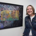 Jane Lindsey stands next to her oil pastel and China marker painting Dark Matters in the Juneau Arts and Humanities Councils Juried Art Show for First Friday on Friday, June 7, 2019. (Michael Penn | Juneau Empire)