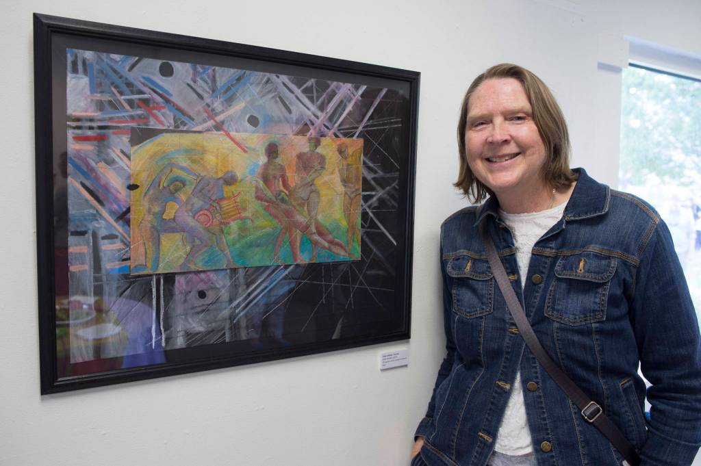 Jane Lindsey stands next to her oil pastel and China marker painting Dark Matters in the Juneau Arts and Humanities Councils Juried Art Show for First Friday on Friday, June 7, 2019. (Michael Penn | Juneau Empire)