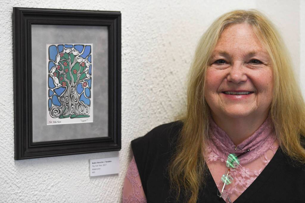 Robin Hiersche stands next to her watercolor painting The Fish Tree in the Juneau Arts and Humanities Councils Juried Art Show for First Friday on Friday, June 7, 2019. (Michael Penn | Juneau Empire)