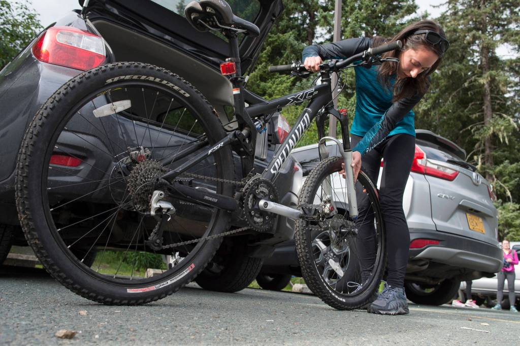 Deborah Reid attaches the front wheel to her mountain bicycle after arriving for a womens mountain bike ride at Dredge Lakes on Thursday, June 13, 2019. (Michael Penn | Juneau Empire)