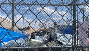 In this June 1, 2019, photo, provided by New Mexico State University professor Neal Rosendorf, migrants are seen through fencing inside a temporary outdoor encampment where theyre waiting to be processed in El Paso, Texas. Rosendorf said it resembled a human dog pound. (Neal Rosendorf via AP)