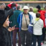 A bear-costumed employee from Holland America Lines Noordam cruise ship checks his phone between sessions being photographed with arriving visitors at Marine Park in this June 2015 photo. 5G mobile network service which GCI announced Tuesday is coming to Alaska, will result in faster device speeds. (Michael Penn | Juneau Empire File)