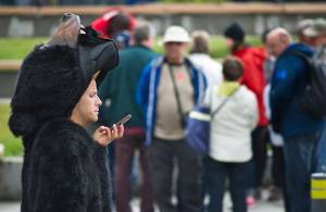 A bear-costumed employee from Holland America Lines Noordam cruise ship checks his phone between sessions being photographed with arriving visitors at Marine Park in this June 2015 photo. 5G mobile network service which GCI announced Tuesday is coming to Alaska, will result in faster device speeds. (Michael Penn | Juneau Empire File)