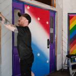 Rendezvous co-manager Asher Rohan paints outside of the downtown Juneau bar, June 26, 2019. (Michael Penn | Juneau Empire)