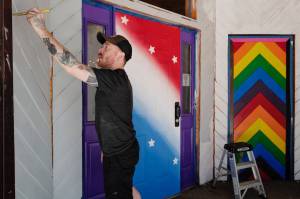 Rendezvous co-manager Asher Rohan paints outside of the downtown Juneau bar, June 26, 2019. (Michael Penn | Juneau Empire)