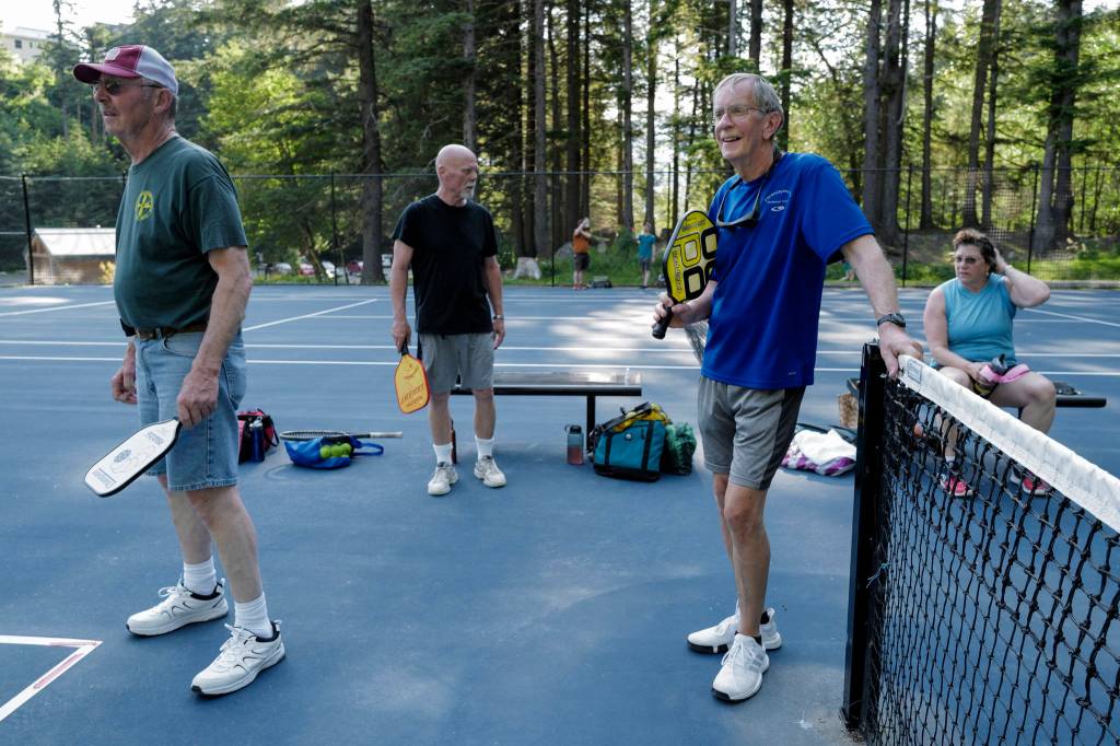 Bob Young, second from left, Barney Norwick, second from right, and Chris Carte, right, rest and wait for their next pickleball game at the Cope Park tennis courts on Wednesday, June 26, 2019. (Michael Penn | Juneau Empire)