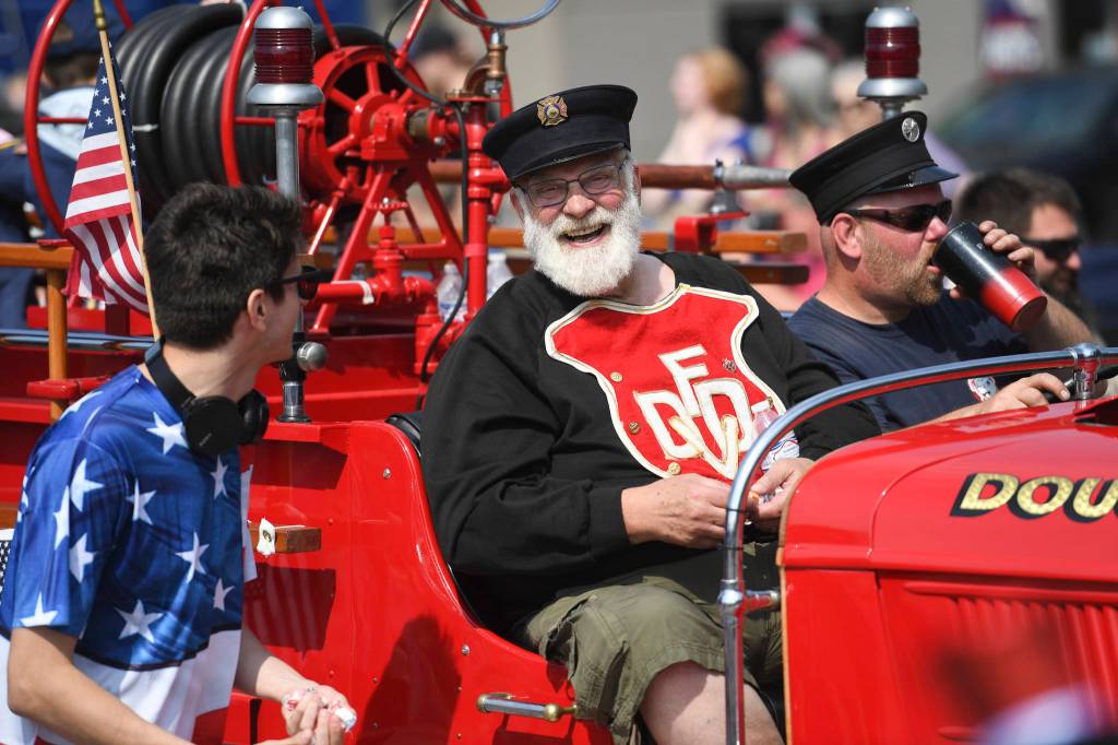 Mike Race, center, rides in a 1937 Ford Fire Engine during the Juneau Fourth of July Parade on Thursday, July 4, 2019. Race was a volunteer fireman for 18 years. (Michael Penn | Juneau Empire)