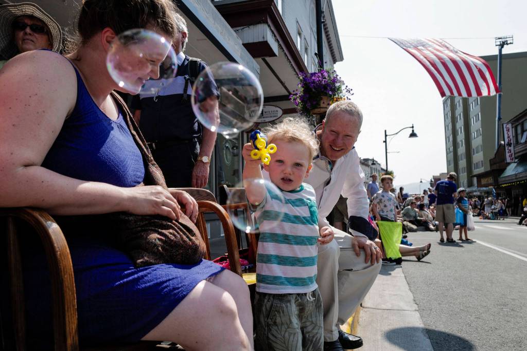 Lisa and Joshua Adams watch their son, Erik, 2, make soap bubbles during the Juneau Fourth of July Parade on Thursday, July 4, 2019. (Michael Penn | Juneau Empire)