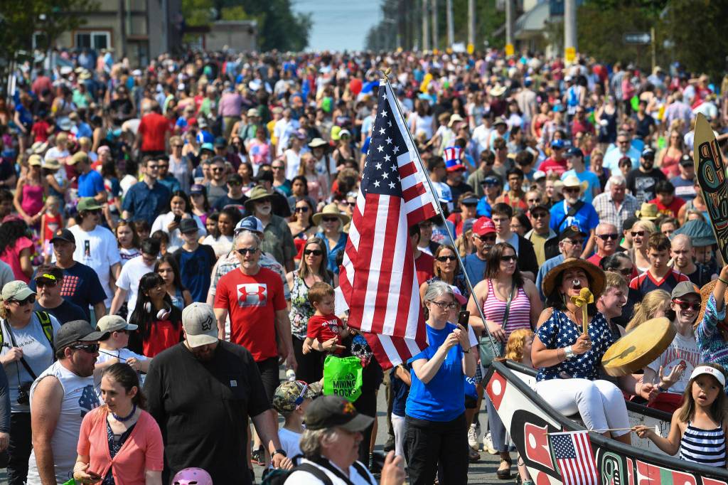 People follow the One Peoples Canoe Society canoe to Savikko Park at the end of the Douglas Fourth of July Parade on Thursday, July 4, 2019. (Michael Penn | Juneau Empire)