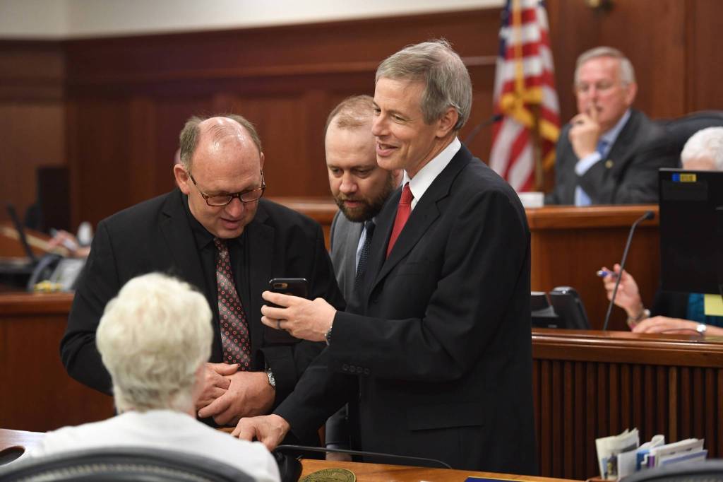 Rep. Matt Claman, D-Anchorage, shows other House members video on his phone of happenings in Wasilla before a Joint Session of the Alaska Legislature to vote on an override of Gov. Mike Dunleavys budget vetoes at the Capitol on Wednesday, July 10, 2019. (Michael Penn | Juneau Empire)