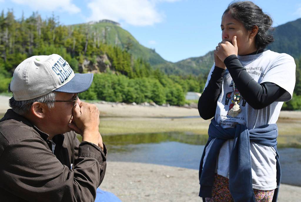 In this photo taken June 20, 2019, Crystal Bullock, of Ketchikan, learns from Alphonse Edwards how to make the call of a Canadian goose during Culture Camp on Hemlock Island near Metlakatla, Alaska. This year was the first time the Ketchikan Indian Community and Nüüm Na Waalt culture camps joined together for the event and a seven-night campout on the island. (Dustin Safranek/Ketchikan Daily News via AP)