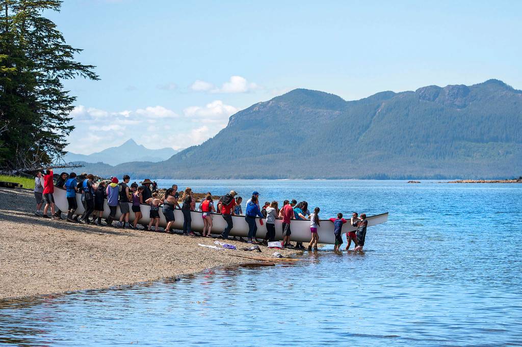 In this photo taken June 20, 2019, children and chaperones with the Ketchikan Indian Community and Nüüm Na Waalt culture camps move a Tsimshian war canoe into the water on Hemlock Island near Metlakatla, Alaska. This year was the first time the Ketchikan Indian Community and Nüüm Na Waalt culture camps joined together for the event and a seven-night campout on the island. (Dustin Safranek/Ketchikan Daily News via AP)