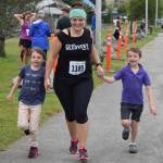Naomi Figley crosses the finish line of the Juneau Marathon and Half Marathon with her stepsons Audria and Andrew Watkins, 8, at Savikko Park on Saturday, July 27, 2019. The running event attracted over 200 runners, the vast majority of which were half marathoners. (Nolin Ainsworth | Juneau Empire)