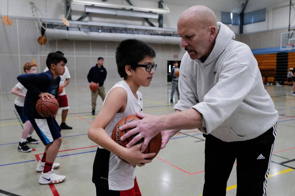 Coach Bob Saviers helps David Friday, 11, with his three-point stance during the Latseen Hoop Camp at Dzantaki Heeni Middle School on Monday, July 29, 2019. The camp runs all week for students entering grades 6-12. (Michael Penn | Juneau Empire)