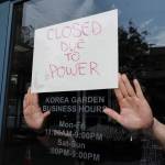 Steven DeVoss, manager of Korea Garden on Front Street, puts up a sign to closed his business before noon on Wednesday, July 31, 2019. (Michael Penn | Juneau Empire)
