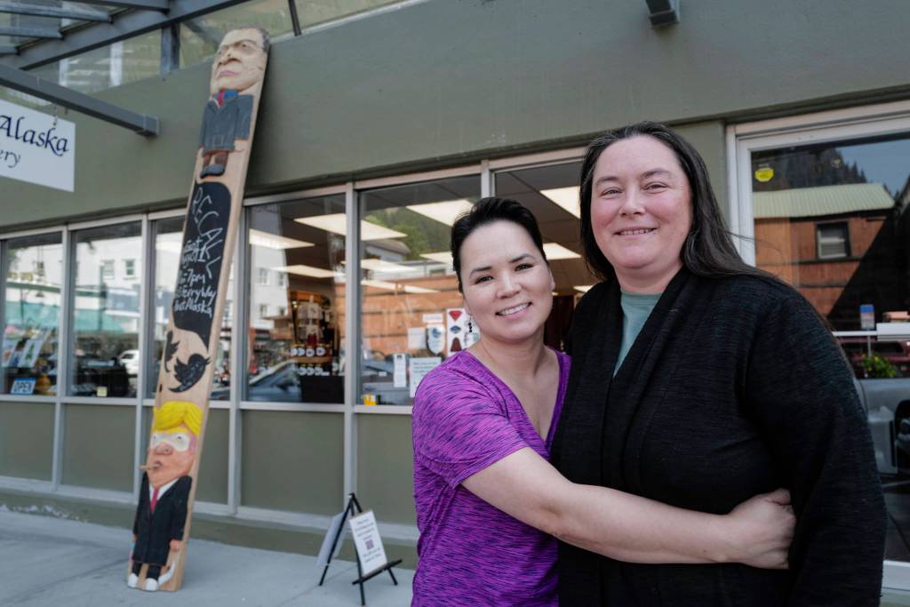Co-owners Aakatchaq Schaeffer, left, and Vivian Mork Yéilk stand in front of their Planet Alaska Gallery with a ridicule pole carved by Sitka artist Tommy Joseph on Wednesday, July 31, 2019. The pole includes likenesses of Alaska Gov. Mike Dunleavy, top, and President Donald Trump. (Michael Penn | Juneau Empire)