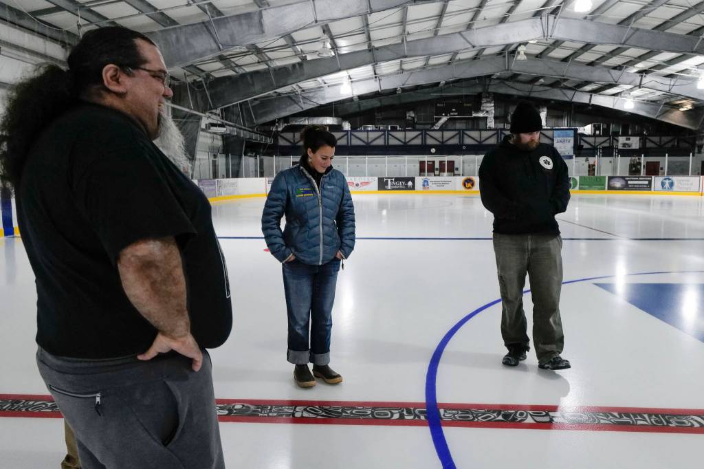 Tsimshian artist Abel Ryan Tsimshian, left, talks Treadwell Arena Manager Lauren Anderson, center, and Program Coordinator Thomas McKenzie about the red line at the Treadwell Arena on Thursday, August 1, 2019. Ryan worked with students in the BAM After School Program to draw animals in Northwest Coast formline designs to be incorporated in the hockey rink ice. The Treadwell Arena opens for the season on Monday. (Michael Penn | Juneau Empire)