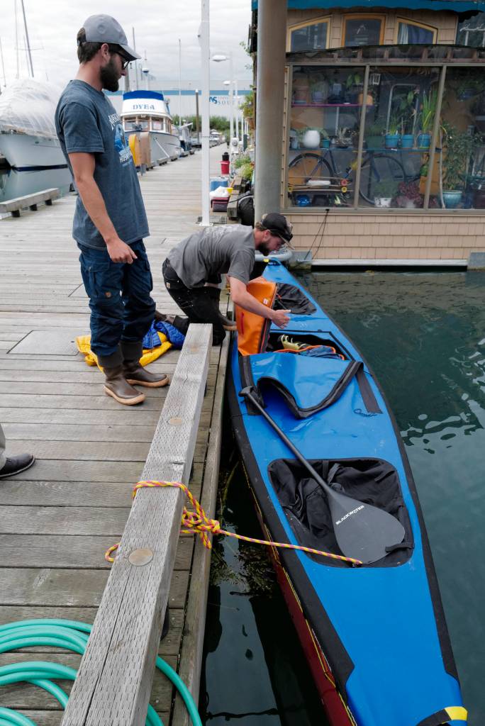 Liam Godfrey-Jolicoeur, right, and Jake Dombek, dig out coastal maps as they talk at Harris Harbor on Thursday, Aug. 2, 2019, about their nearly two-month long trip up the Inside Passage by canoe. Both are orginally from Vermont used the trip to raise money and bring awareness to environmental causes. (Michael Penn | Juneau Empire)