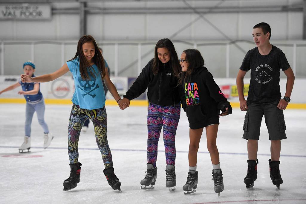 Lashya Bagoyo, 12, left, Christianna Lott, 12, and Malaya Willard, 10, hold hands as they skate with Kelton Griffith, 13, during a free skate on the opening day at the Treadwell Arena on Monday, Aug. 5, 2019. (Michael Penn | Juneau Empire)