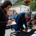 Monika Kunat, left, signs an application petition to recall Gov. Mike Dunleavy with others at the Planet Alaska Gallery on Thursday, Aug. 1, 2019. (Michael Penn | Juneau Empire)