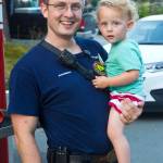 Travis Larsen, paramedic with Capital City Fire/Rescue, poses with his child during National Night Out, Aug. 6, 2019. (Michael S. Lockett | Juneau Empire)