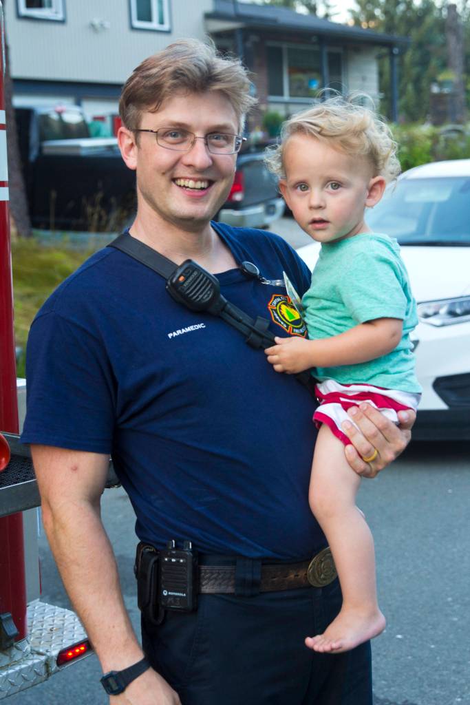 Travis Larsen, paramedic with Capital City Fire/Rescue, poses with his child during National Night Out, Aug. 6, 2019. (Michael S. Lockett | Juneau Empire)