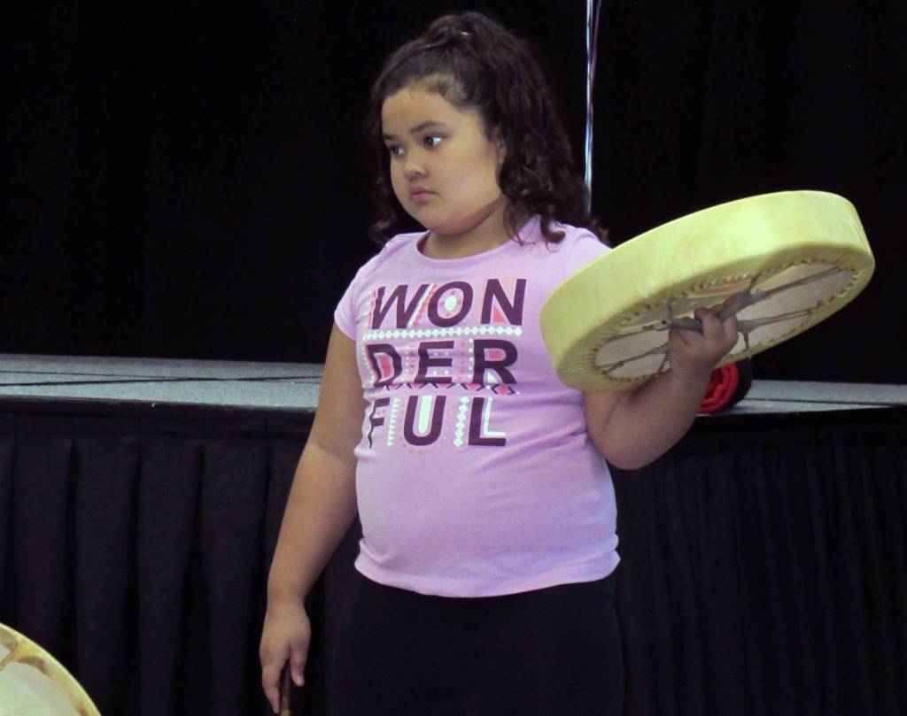 Avalon Iputi,9, holds a drum while looking to Shaksháni éesh Konrad Frank of Woosh.ji.een dance group for instruction during a Molly of Denali event at Elizabeth Peratrovich Hall Saturday, Aug. 11, 2019.