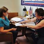 Amanda Ryder, left, signs her application for Municipal Clerk Beth McEwen on Monday, Aug. 12, 2019, to run for one of two open school board seats in this falls municipal election. (Michael Penn | Juneau Empire)
