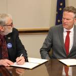 University of Alaska Board of Regents chairman John Davies, left, and Gov. Mike Dunleavy sign an agreement, Tuesday, Aug. 13, 2019, in Anchorage, Alaska, that will spread $70 million in cuts to the university system over three years. That is a sharp reversal from the $135 million cut Dunleavy earlier proposed for this year. (AP Photo/Mark Thiessen)