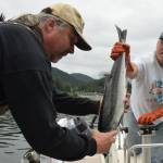 Craig Kahklen hands a silver salmon scholarship fish to Rosco Palmer at Auke Bays Don Statter Boat Harbor on Sunday, Aug. 16, 2015 during the third and final day of the 69th annual Golden North Salmon Derby. (Michael Penn | Juneau Empire File)