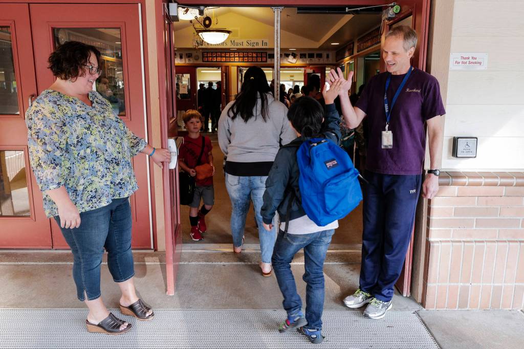 School Counselor Noelle Blanc, left, and Physical Education Teacher Scott May greets students arriving for the first day of school at Riverbend Elementary School on Monday, Aug. 19, 2019. (Michael Penn | Juneau Empire)