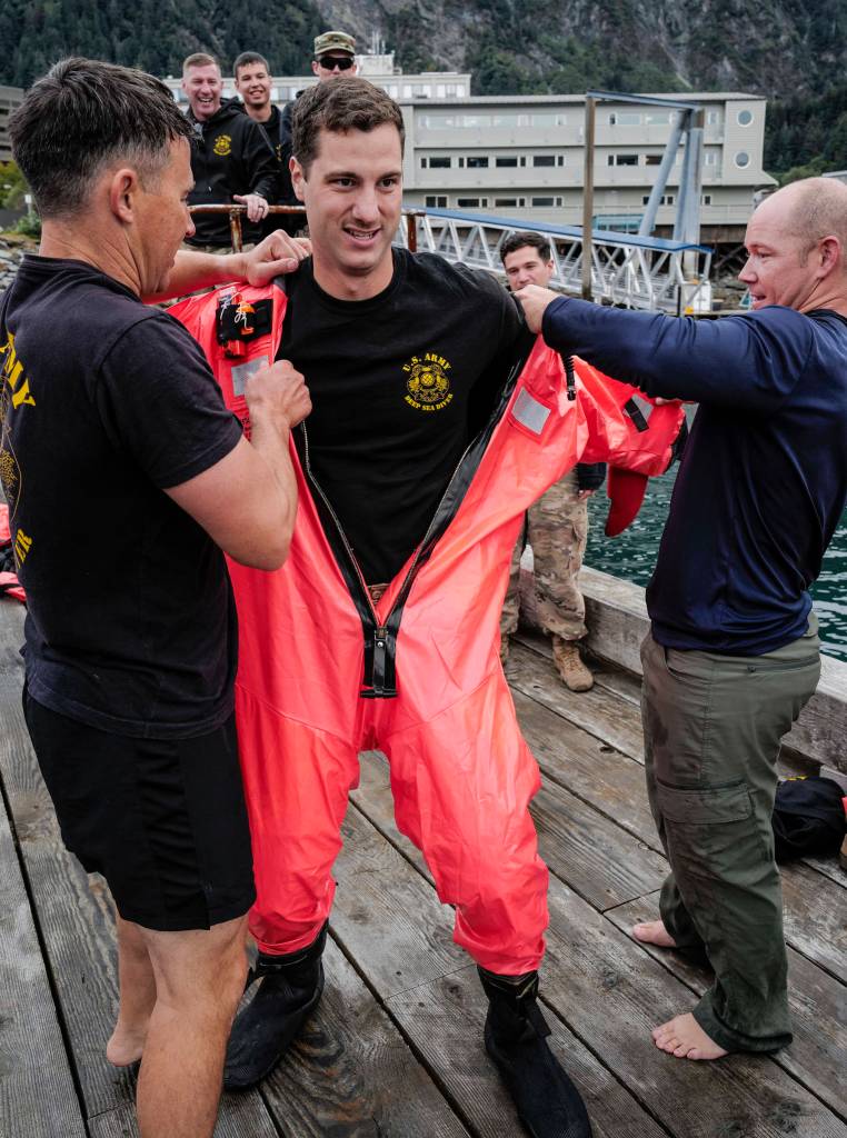 Brett Hyde, of the U.S. Army Dive Team, center, is helped into his survival suit by teammates Daniel Byrd, left, and Shawn Price during the annual Buoy Tender Olympics at Station Juneau on Wednesday, Aug. 21, 2019. (Michael Penn | Juneau Empire)