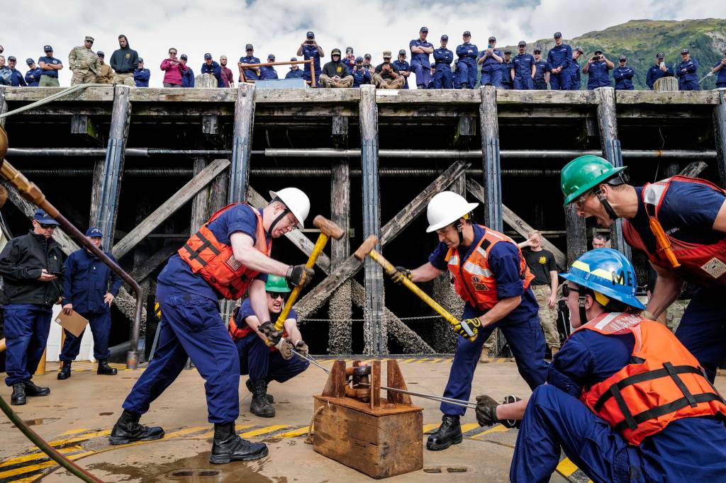 Members of the U.S. Coast Guard Cutter Kukui participate in the heat and beat contest during the annual Buoy Tender Olympics at Station Juneau on Wednesday, Aug. 21, 2019. Lt. Cdr. Ray Reichl, left, swings a sledge hammer with Lt. Cyrus Unvala as teammates Ens. Joseph Snyder and Ens. Victoria Sparacino hold the shackle and Enx. Reid Wiegleb yells encouragement. (Michael Penn | Juneau Empire)