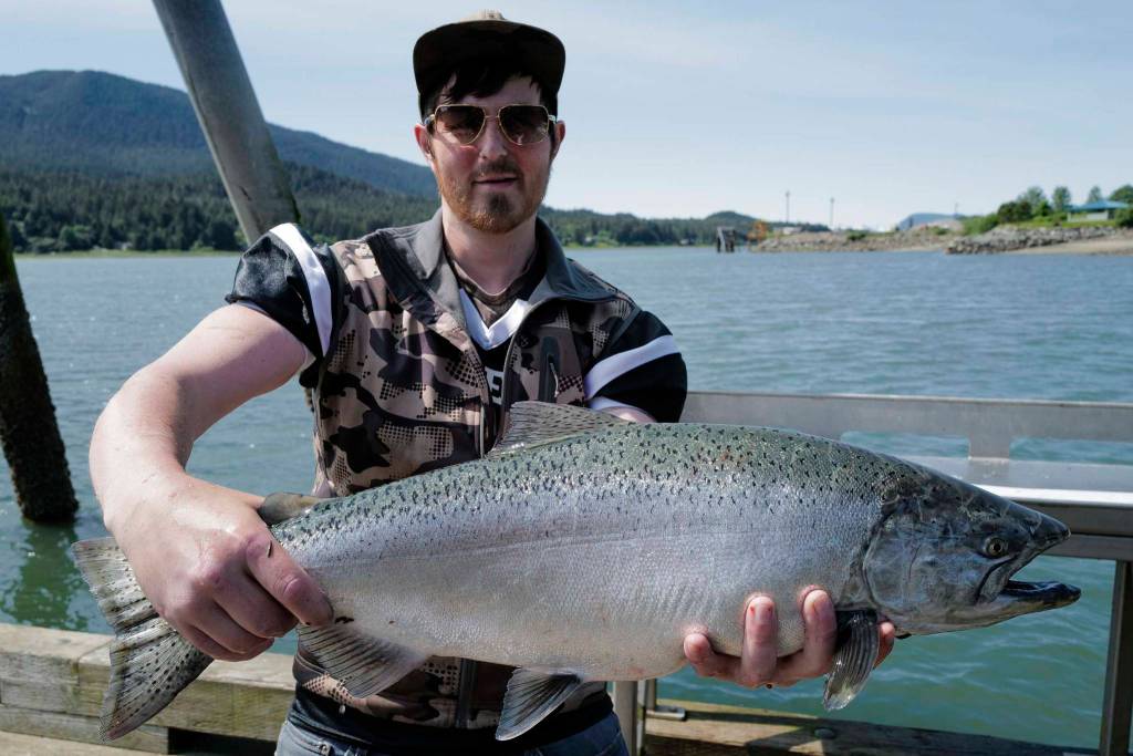 Alexander Masters displays his freshly caught king salmon at the Wayside Park on Channel Drive on Thursday, June 20, 2019. (Michael Penn | Juneau Empire)