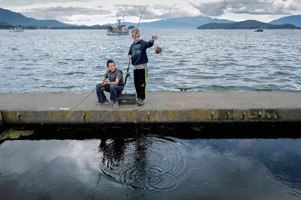 Scott Newman, 10, watches Steel Morgan, 10, pull out a small flounder at the Don D. Statter Memorial Boat Harbor in Auke Bay, on Monday, June 24, 2019. (Michael Penn | Juneau Empire)