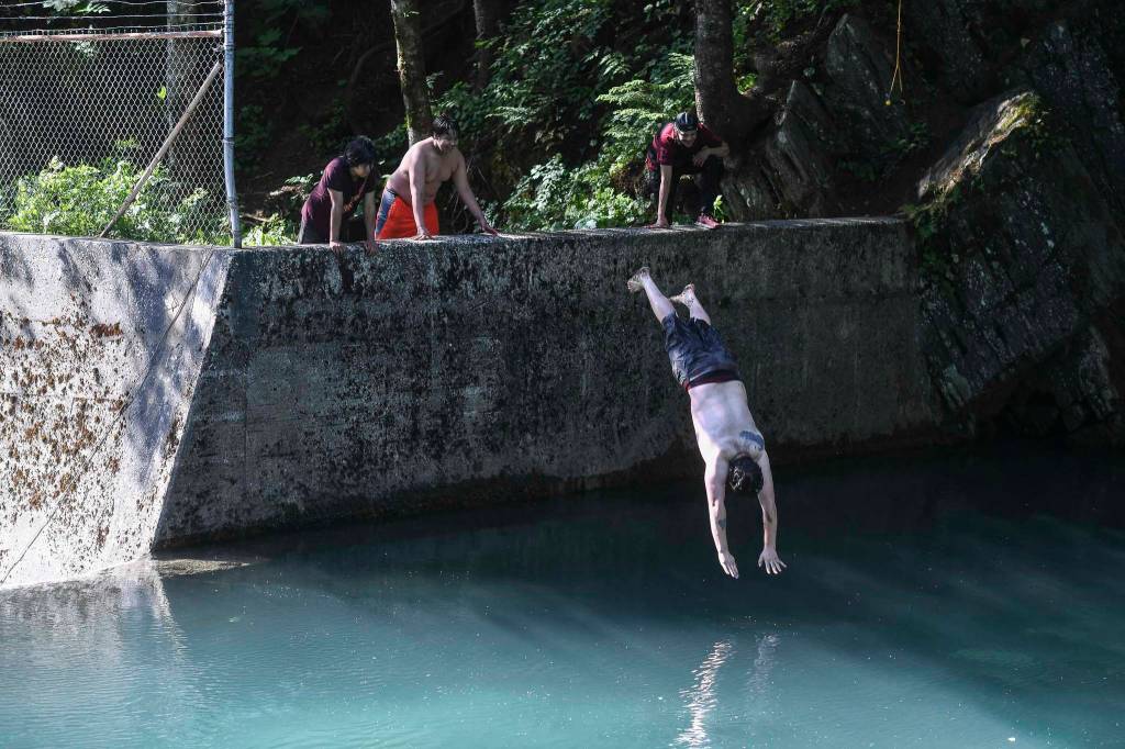 On a warm summer evening Rafael Soto dives into Gold Creek to retrieve eyeglasses for a friend on Wednesday, June 26, 2019. (Michael Penn | Juneau Empire)